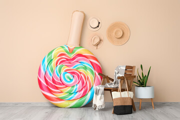 Deckchair with inflatable mattress, summer bag and hanging hats on beige wall. Vacation concept
