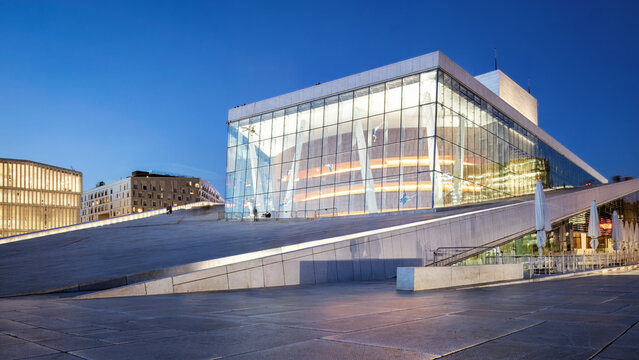 Oslo Opera House illuminated at night, modern architecture with glass facade and sloping roof, creating a stunning urban skyline, Norway - Powered by Adobe