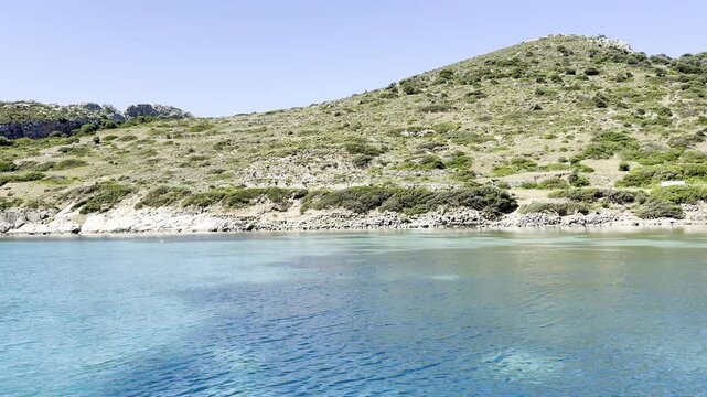  serene coastal landscape featuring clear blue water, a rocky shoreline. Knidos, Turkiye