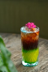 A glass of iced lime roselle drink , edible flower as garnish on top. Tropical drink for summer....