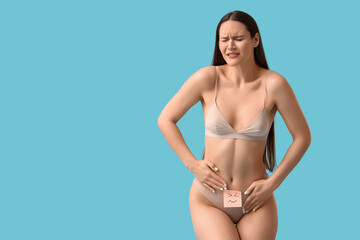 Suffering young woman with sad emoticon on blue background. Cystitis concept