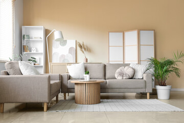 Obraz premium Interior of living room with grey sofas, shelf unit and folding screen