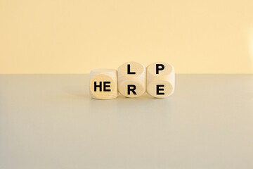 Word transformation. Flipped wooden cubes with word 'help' to 'here'. Beautiful grey table, beige...