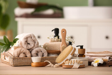 Composition with different cosmetic products, spa accessories and flowers on wooden table in bathroom