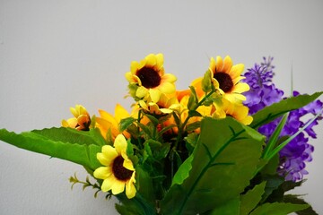 Close up plastic sunflower and lavender with green leaves isolated on horizontal ratio plain gray background.