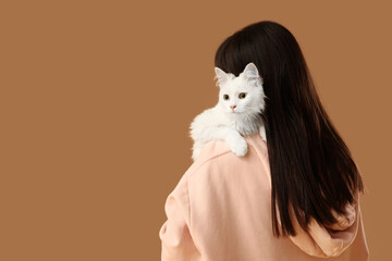 Beautiful young woman with cute white cat on brown background, back view