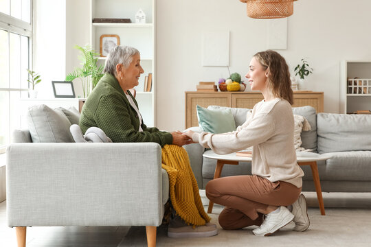 Senior woman with her granddaughter holding hands on sofa at home