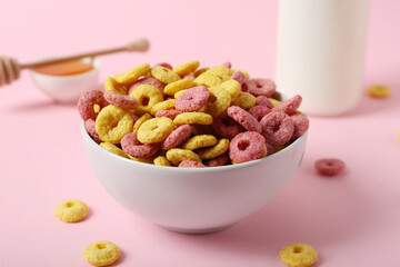 Bowl with tasty cereal rings on pink background