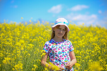 Young girl standing in a field of yellow flowers on a sunny day
