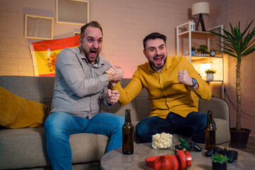 Friends celebrating a sports win while enjoying snacks at home
