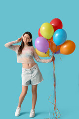 Beautiful teenage girl in headphones with colorful air balloons on blue background