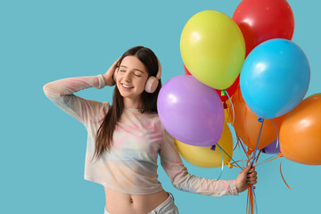 Beautiful teenage girl in headphones with colorful air balloons on blue background