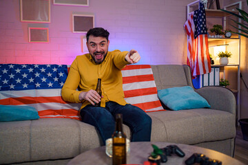 Obraz premium Man enjoying a lively moment on a couch with an American flag