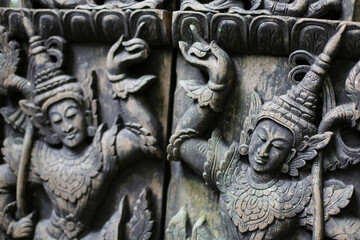 A carved wooden door with Thai deity motifs is commonly found in Thai temples.
