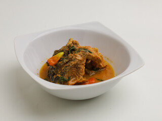 Fish cooked in curry sauce, in white bowl