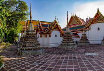 Ornate stupas and colorful temple roofs with golden decorations in the historic Wat Pho complex...