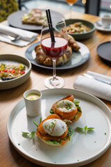 Delicious brunch spread featuring poached eggs on a plate, fresh greens, and a vibrant cocktail in the background. Perfect setting for a morning meal.