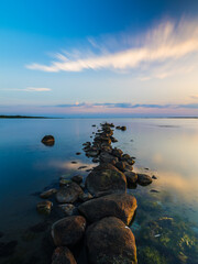 Coastal nature reserve in Sweden showcases a serene stone pathway at sunset over tranquil waters
