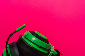Bright green gaming headset with microphone on vibrant pink background. Bold composition in pop-art style, ideal for Gen Z themes and tech visuals. High quality photo