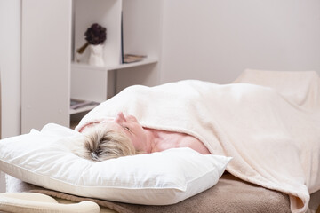 Client enjoying relaxation while lying under a soft towel during a massage session. Peaceful setting designed for tranquility and stress relief, emphasizing comfort and calm
