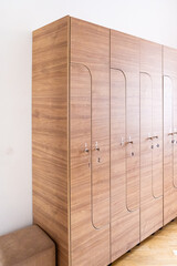Wooden locker unit with multiple numbered doors, each equipped with a key for secure storage....