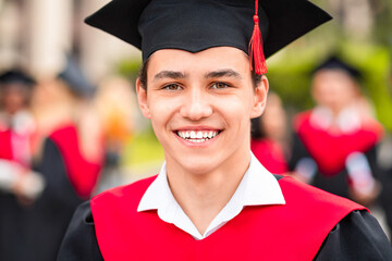 Closeup portrait of happy guy student wearing graduating costume. Positive smiling male student...