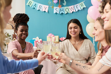 Group of young adult and middle aged women of diverse ethnicities sitting together smiling and...