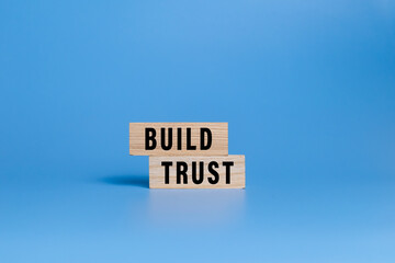 male hand putting wooden blocks with build trust words isolated on blue background