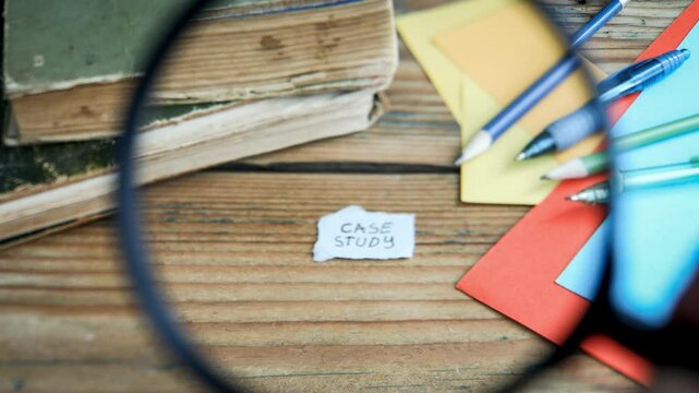 Case Study Concept. Magnifying glass on a wooden textured office table. 4K Video