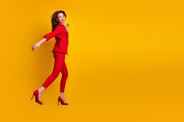 Fototapeta na wymiar Fashionable young woman posing confidently in a vibrant red suit against a yellow backdrop, exuding charm and modern elegance