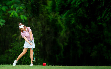 A woman is swinging a golf club
