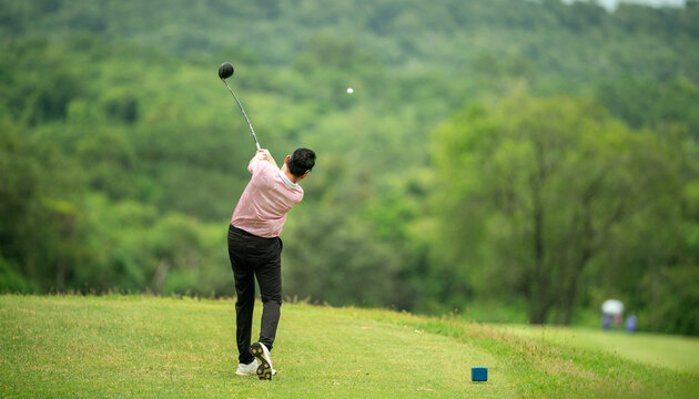 A man is swinging a golf club on a green course