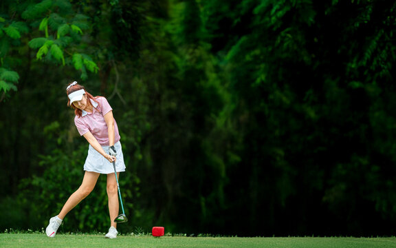 A woman is swinging a golf club - Powered by Adobe