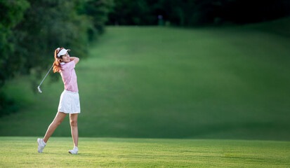 A woman in a pink shirt and white skirt is swinging a golf club