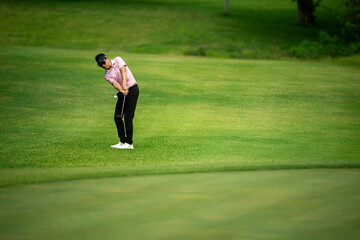 A man is playing golf on a green field