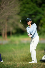A woman is swinging a golf club