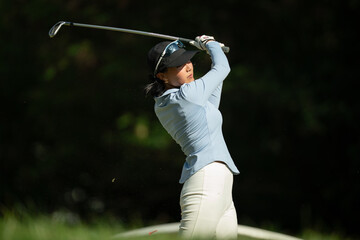 A woman is swinging a golf club