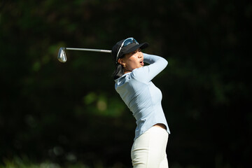 A woman is swinging a golf club