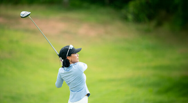 A woman is swinging a golf club