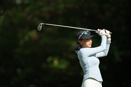 A woman is swinging a golf club