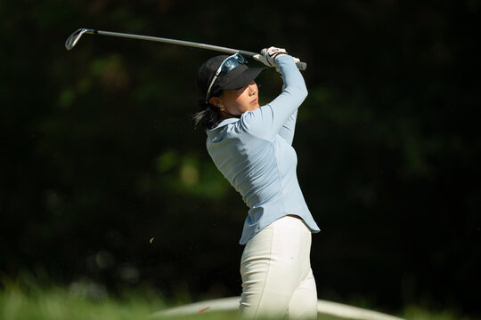 A woman is swinging a golf club