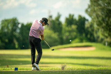 A man is swinging a golf club on a green course
