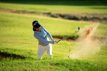 A woman is playing golf and swinging her club