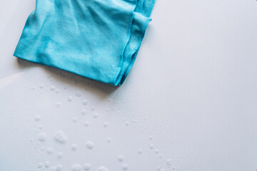 Blue cloth hanging on a white handle next to a window with visible dust and water stains. High quality photo