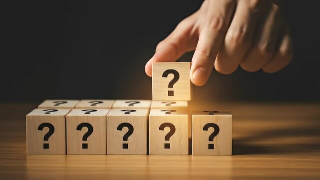 Wooden Blocks With Question Marks Displayed Against Dark Background With Focused Lighting