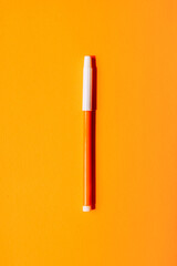 Bright orange marker with white cap centered on a vivid orange background, minimal back to school pop art concept. High quality photo