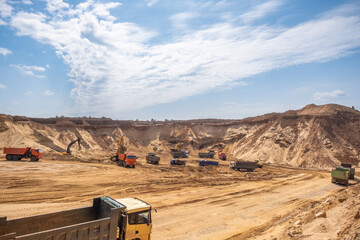 Active work in a sand quarry. Bucket trucks load sand into trucks.