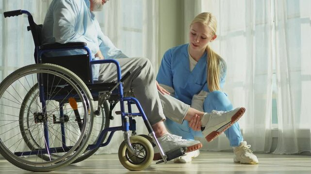 Help support retirement healthcare. Nurse helping old man in wheelchair. Patient and woman in nursing home for medical caregiver. Nurse taking care of paralyzed man in chair for people with disability