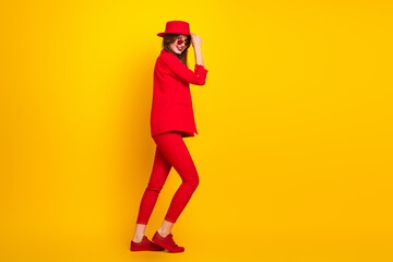Stylish young woman in vibrant red outfit against yellow background, embodying modern fashion, elegance, and confidence