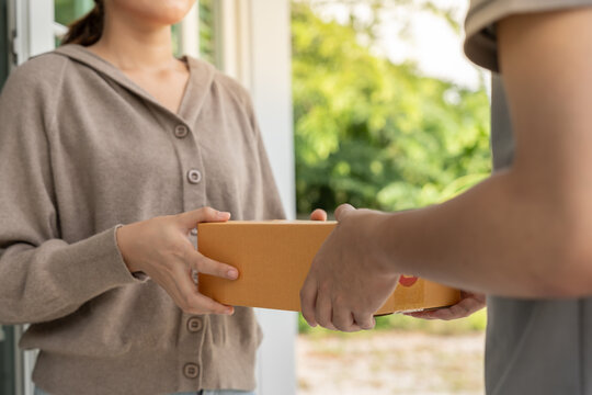 Happy smiling woman receives boxes parcel from courier in front house. Delivery man send deliver express. online shopping, paper containers, takeaway, postman, delivery service, packages